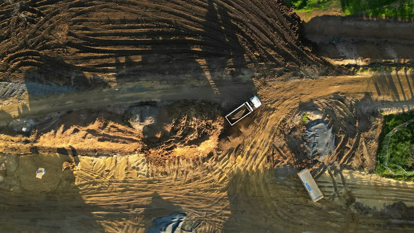 An aerial view of a large site being levelled, with a tipper crossing it
